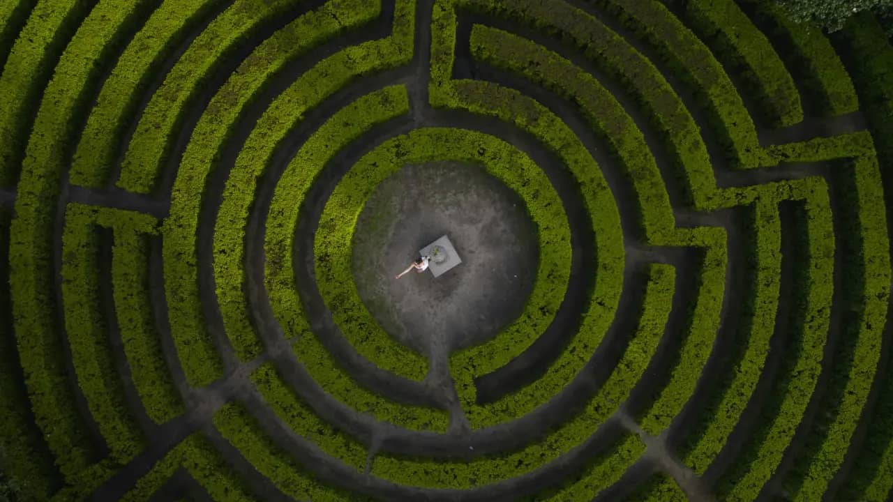 Ein großes, rundes Labyrinth von oben mit einer Frau in der Mitte, die Ihre innere Mitte sucht
