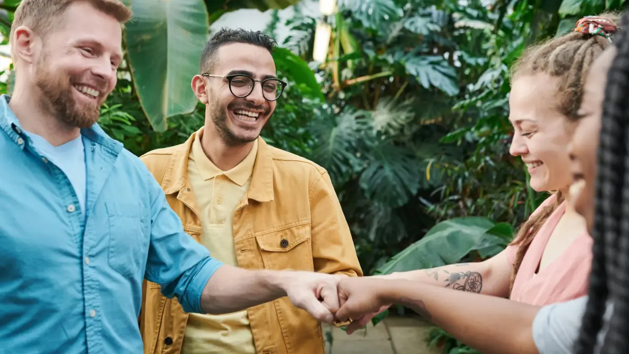 Eine Gruppe junger Menschen hält die Fäuste in der Mitte zusammen, um Zusammenhalt zu signalisieren