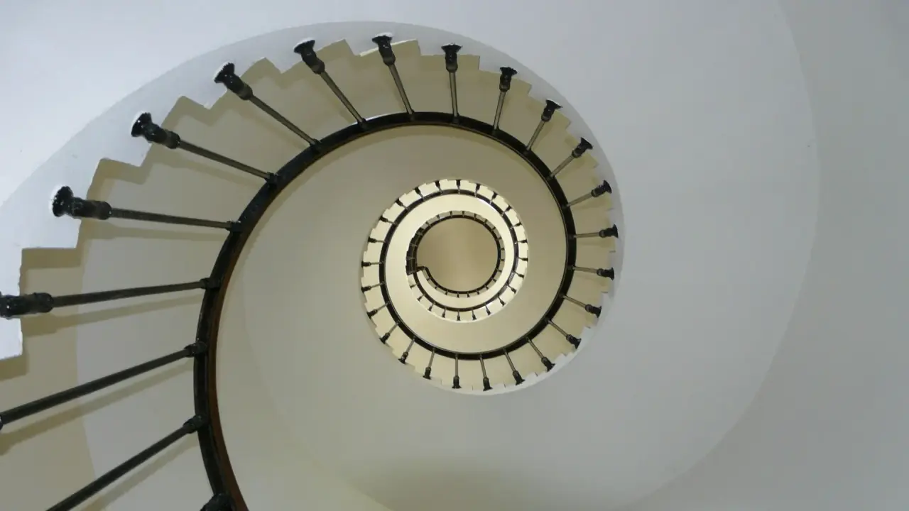 Blick von unten eine mehrere Stockwerke hohe Wendeltreppe hinauf