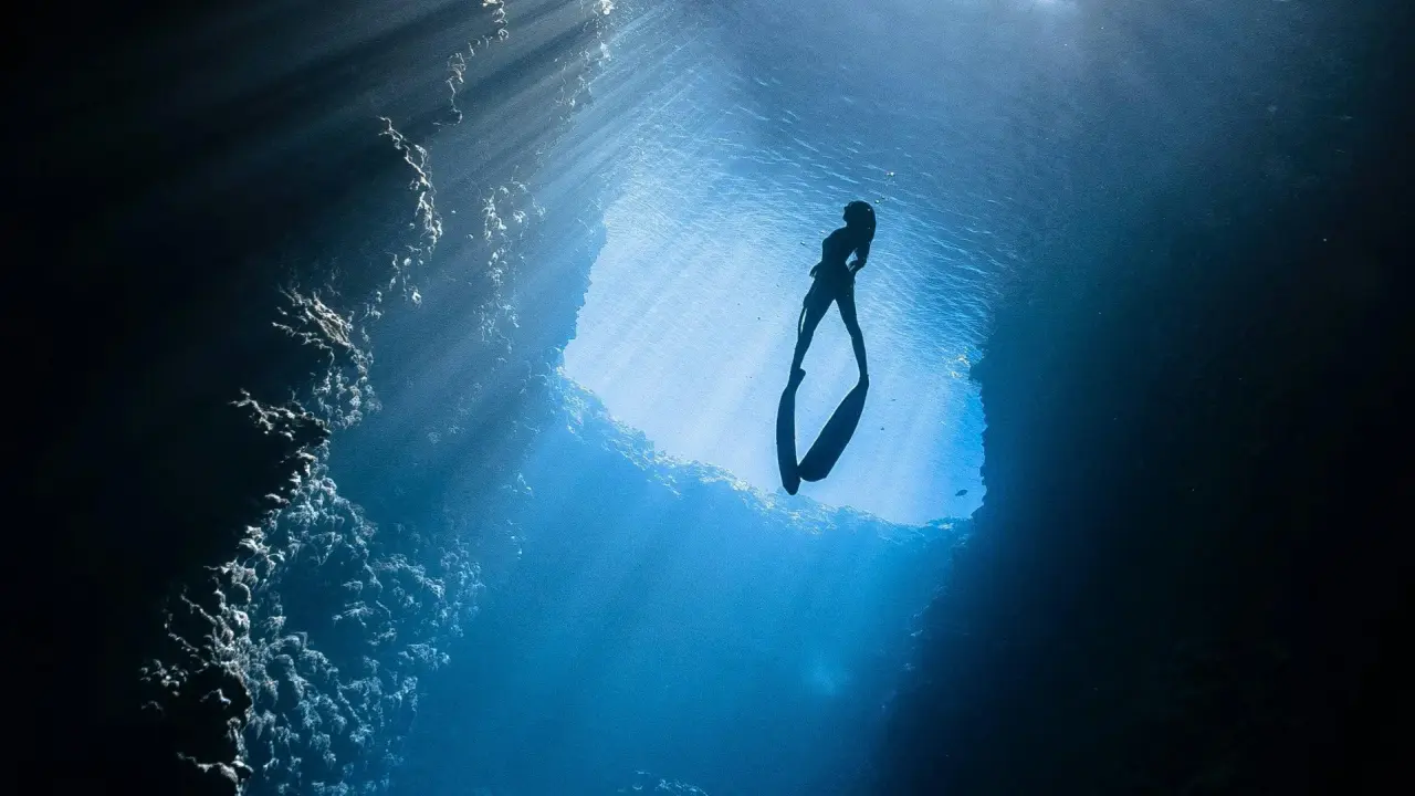 Eine Frau im Wasser taucht der Wasseroberfläche entgegen